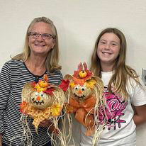 2 smiling ladies holding fall crafts they created at Kewaunee Public Library