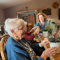 2 women displaying their potted floral creations at an assisted living facility in Kewaunee