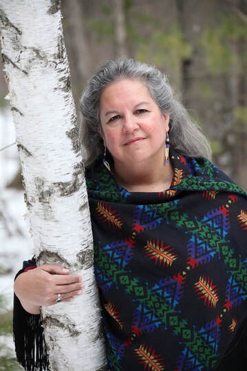 Robin Wall Kimmerer is standing with her arm around a birch tree