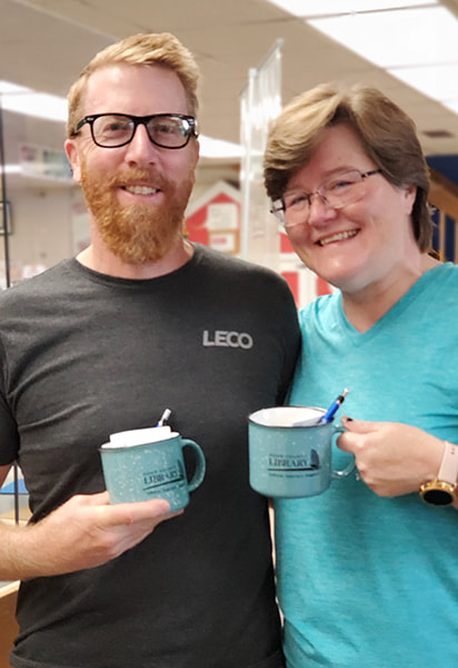 Smiling patrons holding Door County Library mugs, pens and sticky notes