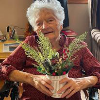 elderly lady holding her potted floral arrangement at assisted living facility in Kewaunee