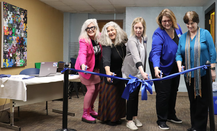 Five people holding scissors get ready to cut a blue ribbon spanning the entry to the JobPod facility at Algoma Public Library