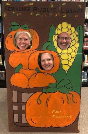 smiling and laughing library library staff posing as pumpkins and corn