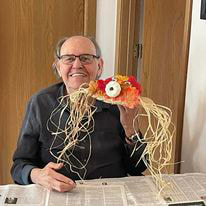 smiling elderly gentleman displaying his fall craft creation at an assisted living center in Kewaunee