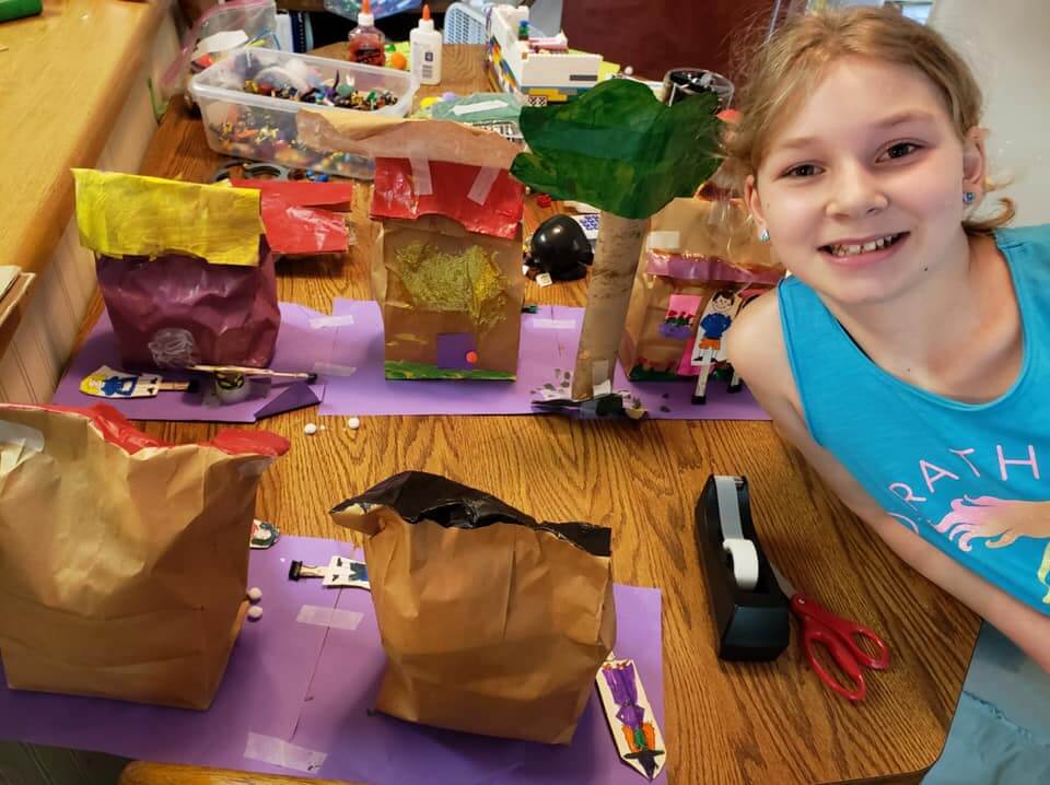 smiling child proudly posing with art projects